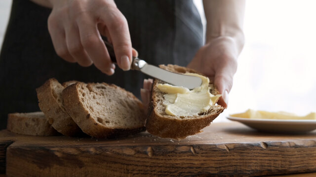 Spreading butter on bread. Woman's hands making sandwich with bread and butter