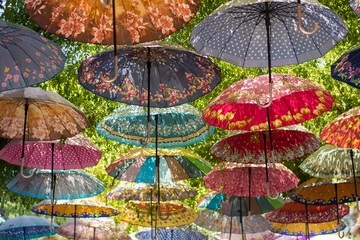 Colorful umbrellas decorating the top of the street. The umbrella serves also as a shade and protection against the sunshine. 