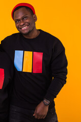 Handsome African American man posing in black sweatshirt on a yellow background. Youth street fashion photo with afro hairstyle.