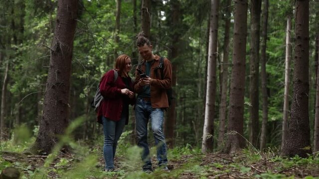 young couple tries to figure out how to navigate using their phone in the forest