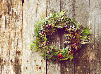 Home made Christmas wreath hanging on a rustic wall in winter.
