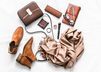 Suede shoes, cashmere scarf, bag, cosmetics, organizer on a light background, top view. Fashion concept