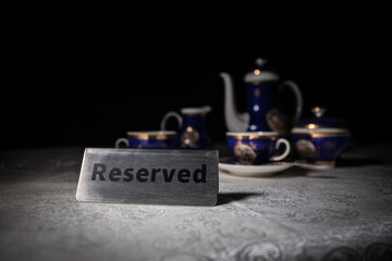 Reserved sign on the table. A tag of reservation placed on the wood table. Metal tag with reservation on dark. Reserved table in a restaurant. Creative concept with colorful lights.