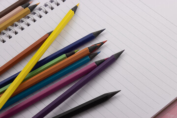 Multicolor blackwood pencils are laid out on a spiral notebook. Back to school, copy space