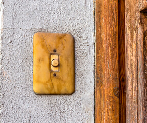 VIEW OF AN OLD BELL PUSH BUTTON ON THE WALL TO CALL ON A HOUSE DOOR