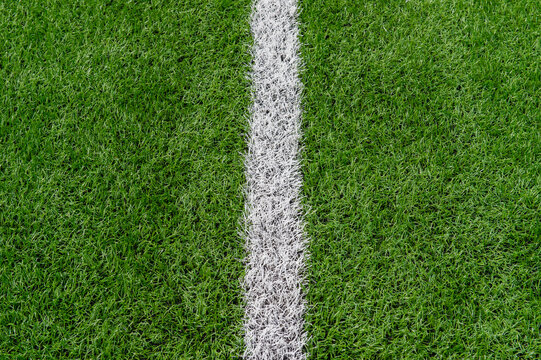 Green synthetic grass sports field with white line shot from above. Soccer, rugby, football, baseball sport concept