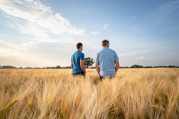 Fototapeta na wymiar Landwirtschaft - Agrarpolitik, nachdenklicher Landwirt mit seinem Sohn im Getreidefeld