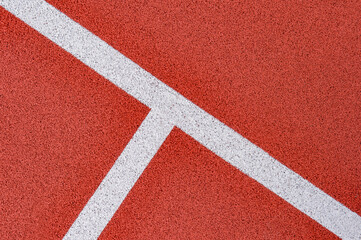 Fototapeta na wymiar Close up on a white line in artificial red turf, on a street basketball, handball, volleyball, futsal, rugby, hockey and football field, in a sports background