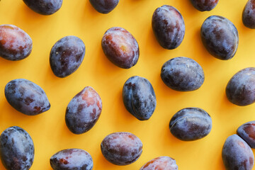 Plums on yellow background. Top view. Summer fruits background.