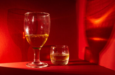 Copa y vaso con ron servido en un bar elegante. Esta foto tiene un fondo rojo. Perfecto para las fiestas y reuniones familiares como la navidad, año nuevo o en una cita romántica 