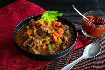 Moroccan Beef Stew with Harissa: A bowl of spicy beef and vegetable stew served with harissa sauce on the side.