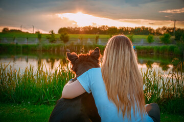 Zabrowo, Poland - June 08, 2020: Capture a young girl with her dog watching sunset near the pond