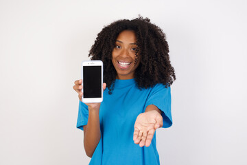 Young african woman with curly hair wearing casual blue shirt with a mobile. presenting smartphone