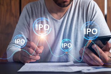 Double exposure of man signing contract with phone and ipo hologram. Concept of initial primary...