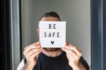 Man holding lightbox with text Be safe in his hand