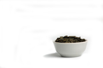 Fototapeta na wymiar bowl of peeled pumkin seeds isolated on white background