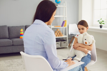 Young Psychologist is talking with a child in the room.