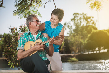 Grandfather and grandson singing and playing ukulele.