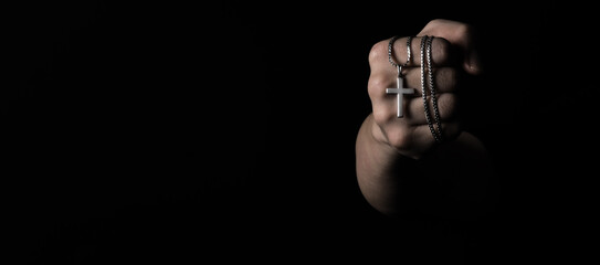 Crucifix pendant or cross sign made from silver and hold in man hand. represent praying for someone...