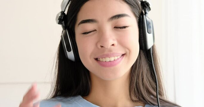 Happy woman listening music using headphones at home