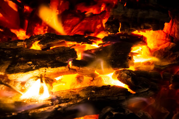 Red coals with fire on black background. Burning coals and wood in fire. Burning wood to keep warm and heat. Glowing embers in hot red, orange color. abstract background. Texture fire bonfire embers