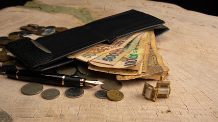 Old coins, fountain pen, wallet, cufflinks and more on a rustic wooden surface, selective focus.