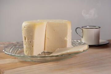Minas cheese and coffee cup arranged on a table with beige tablecloth and gray fudo, selective focus.
