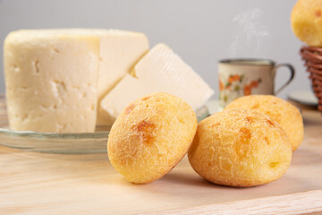 Minas cheese, cup of coffee and cheese bread from Brazil, arranged on a table with beige tablecloth and gray fudo, selective focus.