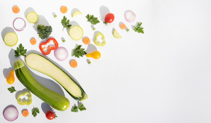 Composition of whole and sliced zucchini with vegetables on a white plate with space for text. Background with food.