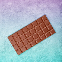 Bar of milk chocolate on color gradient background