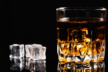 Low key, a glass of whiskey, cognac or bourbon ice scattered nearby, old type of fashion, copy space, selective focus, there is where to write text