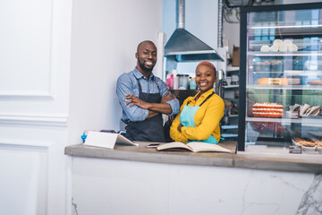 Joyful black man and woman in uniform smiling at camera with crossed arms