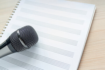Microphone on a blank musical white sheet close up. Singing, writing music, karaoke online,...