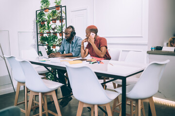 Black remote worker watching laptop calling on phone taking break with coworker