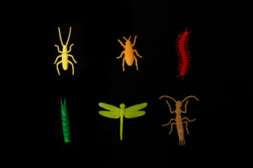 plastic toy insect on the black background, orange beetle tick, green caterpillar, red centipede or millipede, black ant, isolated, close up