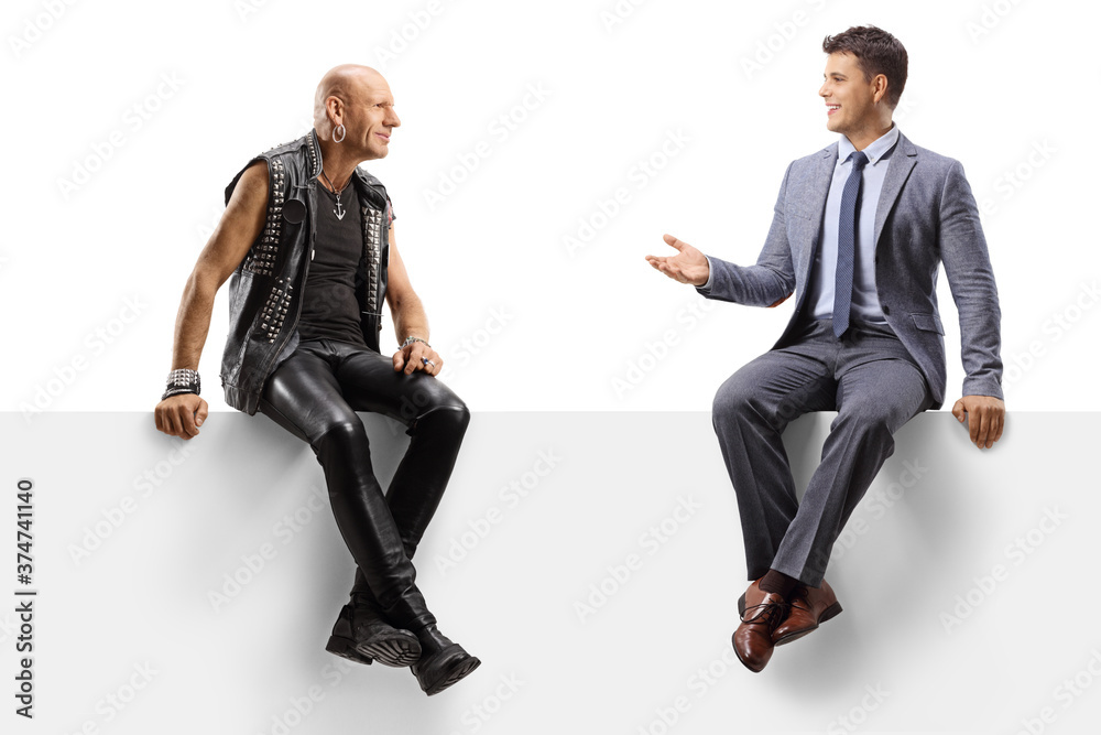 Poster Punk talking with to a young man in a suit and tie while sitting on a panel