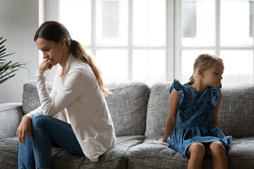 Unhappy different female generations family sitting separately on sofa, ignoring avoiding talking...