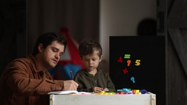 father and son draw on the table at home