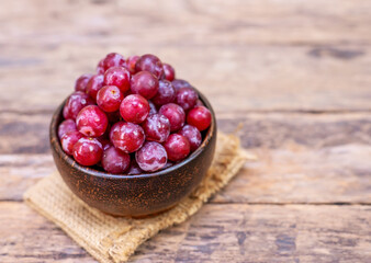 Red grape fruit in wooden bowl on blurred