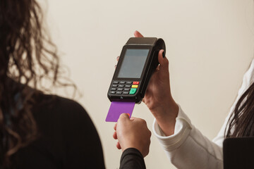 Woman at cash counter holding an electronic card payment machine.