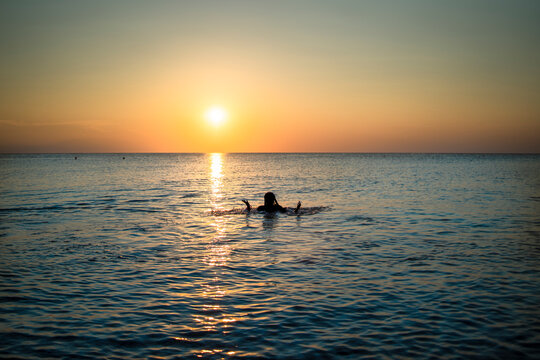 a girl bathing in the sea at sunset