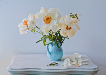 Still life with white peonies in a blue vase against the background of a spruce wall