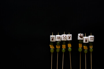 Halloween food concept, marshmallow with face with grapes, gooseberries and cheese, on dark background. healthy snacks kids