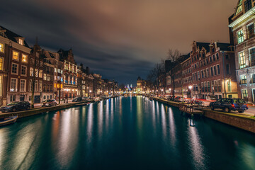 Night city view of Amsterdam canal and old famous dancing houses, Netherlands.