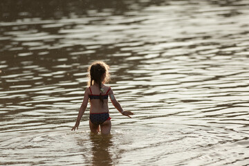 a girl with diabetes walks along the river bank in a swimsuit with a glucose diagnostic sensor on her arm.