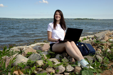 Young woman using laptop computer on sunbed on a beach. Freelance work concept, Freelancer outside