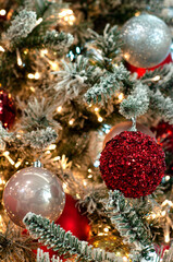 Obraz na płótnie Canvas Decorated Christmas tree closeup background. Red and silver balls and illuminated garland with flashlights. New Year baubles macro photo with bokeh. Winter holiday decoration