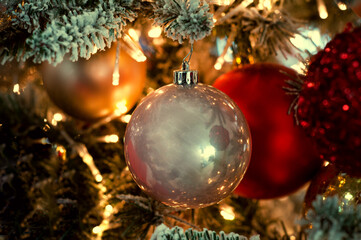 Decorated Christmas tree closeup background. Red and silver balls and illuminated garland with flashlights. New Year baubles macro photo with bokeh. Winter holiday decoration