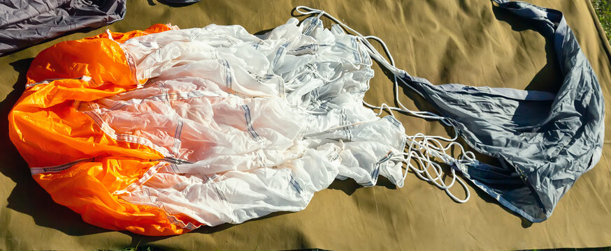 The parachute lies on the grass for assembly and further jump