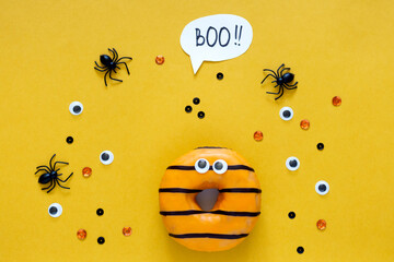 Happy halloween holiday concept. Funny food for kids - scared donuts bright yellow background with...